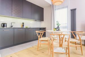 a kitchen with wooden chairs and a table in a kitchen at Novis Apartments Panorama View in Warsaw