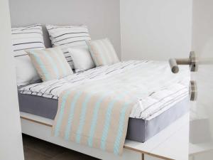 a bed with white and blue striped sheets and pillows at Lotsenstieg 2 Kajuete 05 in Ostseebad Karlshagen