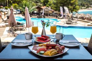 a table with a plate of food next to a pool at Blue Green Bay in Panormos Skopelos