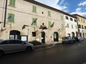 dwa samochody zaparkowane przed budynkiem z zielonymi okiennicami w obiekcie " Il Bersagliere " Dependance Hotel la Pace w mieście Asciano