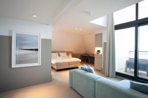 ein Schlafzimmer mit einem Bett und einem Sofa in einem Zimmer in der Unterkunft Strandhotel in Cadzand-Bad