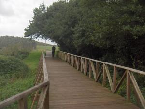 a man walking across a wooden bridge at Apartamentos Playa Galizano in Galizano