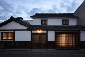 una casa blanca con techo negro y dos puertas en 滔々 御崎 町家の宿 toutou Onzaki Machiya no Yado en Kurashiki