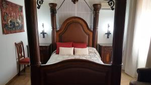 a wooden bed with two red pillows on it at Hotel Rural Hospedería de los Calatravos in La Calzada de Calatrava