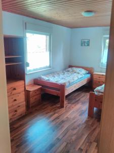 a bedroom with a bed and a window and wooden floors at Ferienpark Sonnenhof in Tambach-Dietharz