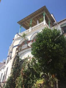 a white building with a balcony and a tree at Pension El Torreon in Mojácar