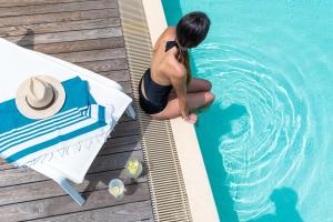 a woman is sitting next to a swimming pool at Hôtel-Résidence la Pinède in Amélie-les-Bains-Palalda