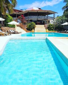 a swimming pool in front of a house at Hotel & Pousada Tatajuba in Canoa Quebrada