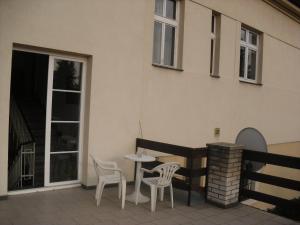 eine Terrasse mit 2 Stühlen, einem Tisch und einem Gebäude in der Unterkunft Pension Hanspaulka in Prag