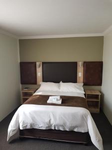 um quarto com uma cama grande e 2 mesas de cabeceira em madeira em Be My Guest Hotel Conference em Sasolburg