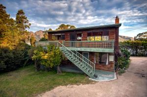 a log house with a staircase in front of it at Beachcroft in Coles Bay