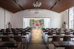 a room with tables and chairs and a stained glass window at AMERON Hamburg Hotel Speicherstadt in Hamburg