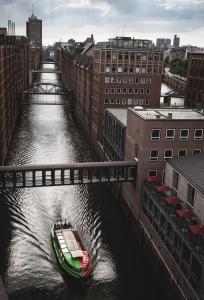 a boat traveling down a river under a bridge at AMERON Hamburg Hotel Speicherstadt in Hamburg