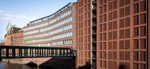 a tall brick building with a bridge next to a river at AMERON Hamburg Hotel Speicherstadt in Hamburg