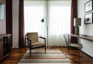 a living room with a chair and a desk and a lamp at AMERON Hamburg Hotel Speicherstadt in Hamburg