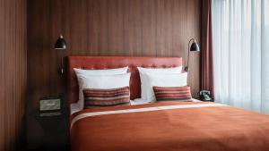 a bedroom with a large bed with an orange blanket at AMERON Hamburg Hotel Speicherstadt in Hamburg