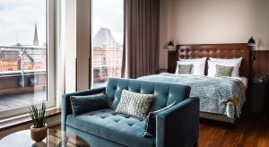 a bedroom with a blue couch and a bed and a window at AMERON Hamburg Hotel Speicherstadt in Hamburg