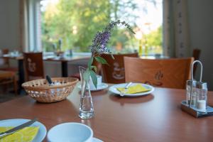 a wooden table with a vase with a flower in it at Pension Thieshof in Amelinghausen +14 photos