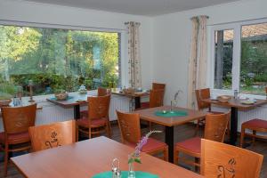 a restaurant with wooden tables and chairs and windows at Pension Thieshof in Amelinghausen