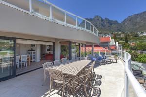 a patio with a table and chairs on a balcony at position, Position, POS-ITION! Adjacent CB Beach in Cape Town