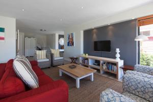 a living room with red furniture and a flat screen tv at position, Position, POS-ITION! Adjacent CB Beach in Cape Town