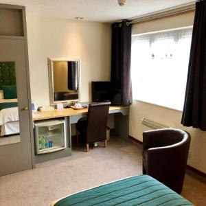 a bedroom with a desk with a computer and a mirror at Best Western Compass Inn in Tormarton