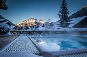 a hot tub covered in snow in front of a mountain at Hotel Cirelle Suite & Spa in Canazei