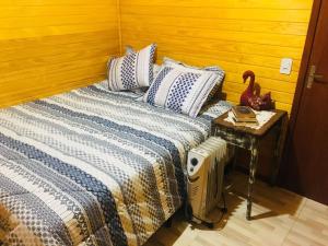 a bed with a blue and white blanket and a side table at Casa de Campo Vale Rio dos Bugres in Urubici