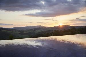 un grande bacino d'acqua con il tramonto sullo sfondo di Castello di Casole, A Belmond Hotel, Tuscany a Casole dʼElsa
