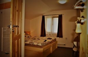 um pequeno quarto com uma cama e uma janela em Penzion U Médi em Cesky Krumlov