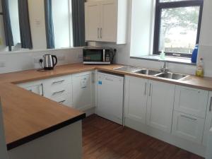a kitchen with white cabinets and a sink and a microwave at Torrin Bunkhouse in Torrin