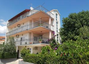 ein weißes Gebäude mit Balkonen und Blumen in der Unterkunft Apartments Krizanac in Trogir