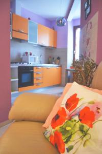 cocina con armarios de color naranja y sofá con almohada en B&B La Casa d'Artista, en Ortignano Raggiolo