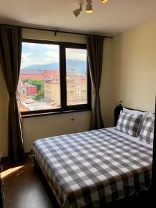 ein Schlafzimmer mit kariertem Bett und großem Fenster in der Unterkunft Golden Dome view Apartment in Sofia