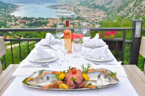 Apartments Vidikovac Inn في كوتور: طبق من السمك على طاولة مع كؤوس للنبيذ