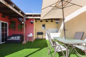 un patio con mesa, sillas y sombrilla en Villa Blanca Tenerife - Private rooms - Terrace and BBQ, 5 minutes from the beach and airport, en San Isidro