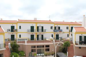 a large white building with green shutters at Apartamento de São João in Praia da Areia Branca