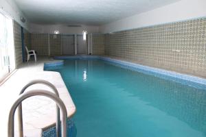 a large swimming pool with blue water in a room at Apartamento de São João in Praia da Areia Branca