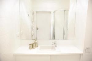 ein weißes Badezimmer mit einem Waschbecken und einem Spiegel in der Unterkunft Apartament Plażowy in Giżycko