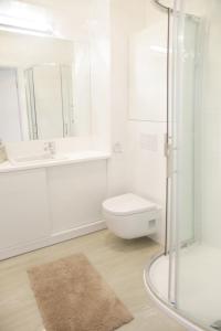 ein weißes Bad mit einem WC und einem Waschbecken in der Unterkunft Apartament Plażowy in Giżycko