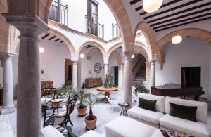 una sala de estar con columnas, sillas y un piano en Palacio Torneria, en Jerez de la Frontera