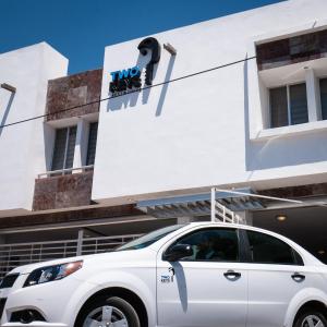 une voiture blanche garée devant un bâtiment dans l'établissement Two Keys, à Torreón