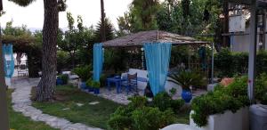 a garden with a gazebo with a blue curtain at Villa Nantia in Agios Georgios
