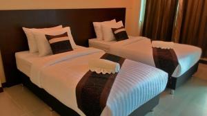 duas camas num quarto de hotel com lençóis brancos em K2 Living Hotel em Uttaradit
