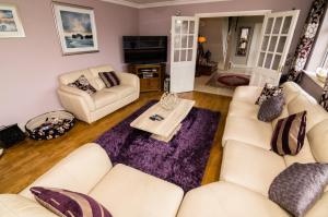 una sala de estar con sofás blancos y una mesa. en Ashbrook B&B, en Killarney