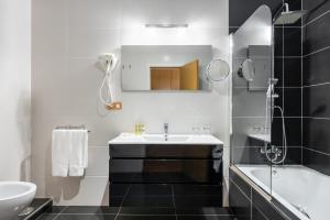 Un baño con lavabo, bañera y espejo. en Eurostars Monumento Monasterio de San Clodio Hotel, en Leiro
