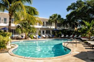 une piscine bordée de palmiers et un hôtel dans l'établissement Tradewinds Apartment Hotel Miami Beach, à Miami Beach