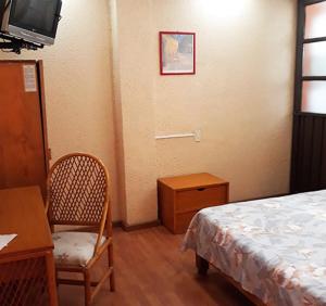 a bedroom with a bed and a desk and a tv at Hotel Canad&aacute; in Toluca