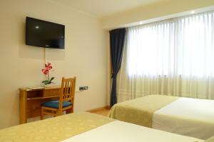 Pokój hotelowy z 2 łóżkami, biurkiem i telewizorem w obiekcie Ñikén Hotel & Spa w mieście Necochea