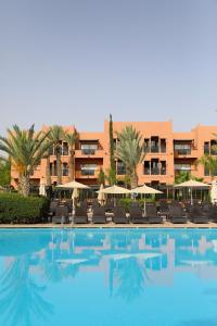 une piscine avec des chaises et un hôtel en arrière-plan dans l'établissement Kenzi Menara Palace & Resort, à Marrakech